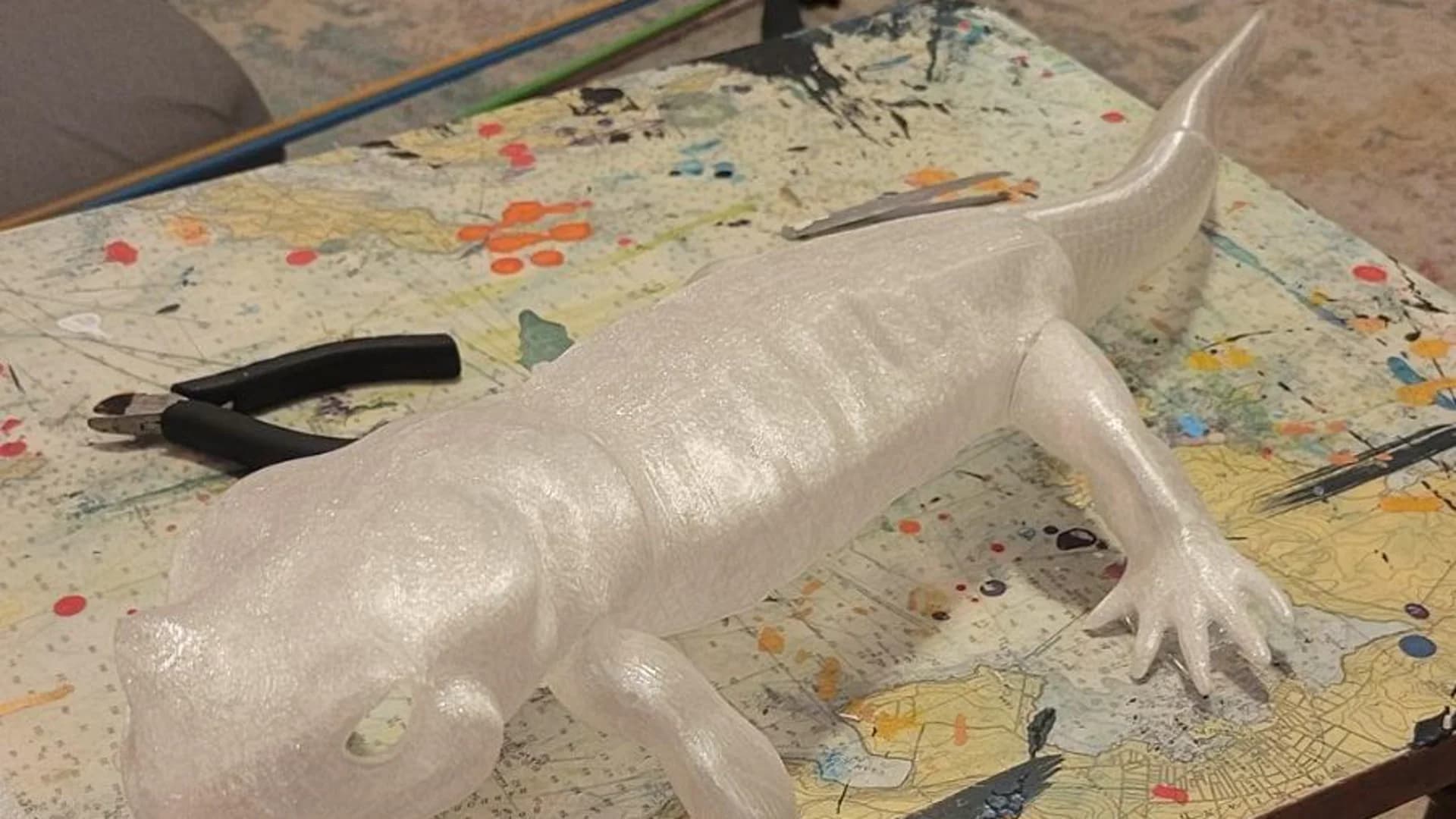 Clear-resin 3D printed salamander assembly with modular segments on the workbench.
