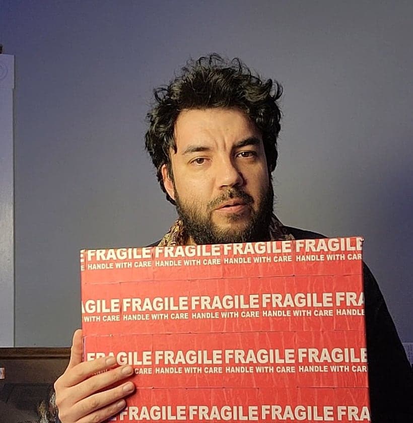 Darrel holding a painting wrapped in red Fragile tape